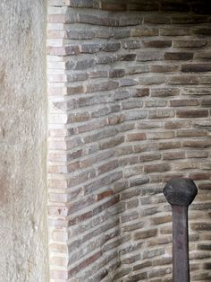 an old metal pole in front of a brick wall