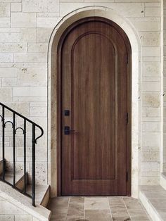 a wooden door sitting on the side of a white brick wall next to a set of stairs