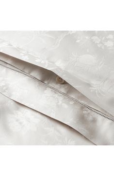 the bottom half of a white bed with an embroidered cover and zippered closures