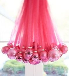 pink ornaments are hanging from a pole in front of a window with bright red hair