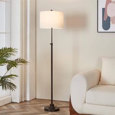 a living room with a white couch and a lamp on the floor in front of a window