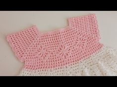 a pink and white crocheted dress on a table