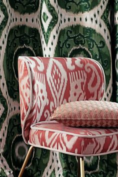 an upholstered chair with a red and white pillow on it's back