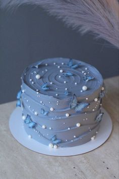 a blue cake with white frosting and butterflies on it