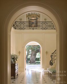 an archway leading to a large tree in the middle of a room with white walls and tile flooring