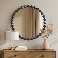 a dresser with a mirror, lamp and vase on it