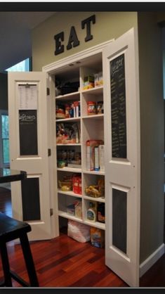 an open pantry with chalkboard on the door and shelves full of food in it