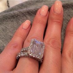 a woman's hand with two engagement rings on her fingers and an engagement ring in the middle