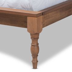 a wooden bed frame with white sheets and pillows on it's headboard, viewed from the bottom