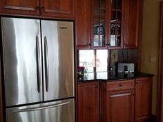 a metallic refrigerator freezer sitting inside of a kitchen next to wooden cupboards and cabinets