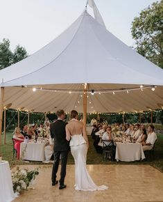 a bride and groom standing under a tent at their wedding reception