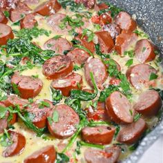 a pizza with sausage, spinach and tomatoes in a pan on the stove top