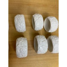 five white carved ceramic objects sitting on top of a wooden table