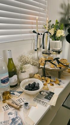 an assortment of food and drinks on a table next to a window with white flowers