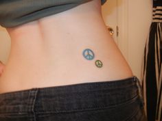 a woman with a small peace sign tattoo on her lower back side ribcage