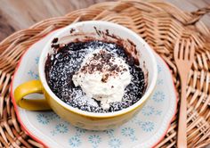 a cup filled with ice cream and chocolate on top of a wicker basket next to a spoon