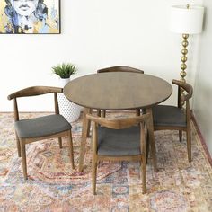 a dining room table with two chairs and a potted plant on the rug in front of it