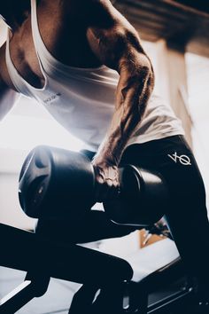 a man is doing exercises on a bench with dumbbells in a gym room