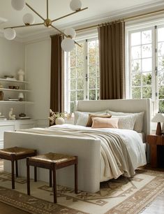 a bedroom with a large bed and two stools in front of the big window