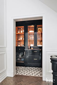 an open door leading into a kitchen with black cabinets and white trimmings on the walls