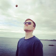 a man wearing sunglasses looking up at an object in the sky