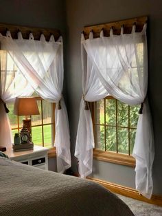 two windows with sheer curtains in a bedroom