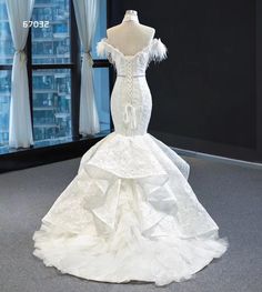 a white wedding dress on display in front of a window with cityscape behind it