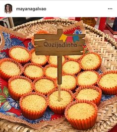 a basket filled with cupcakes sitting on top of a wooden sign next to a pile of muffins