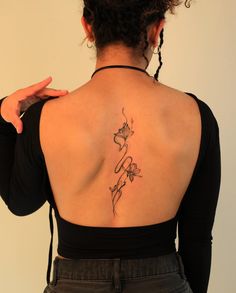 a woman with a tattoo on her back is looking down at the camera and holding her hand up to her shoulder