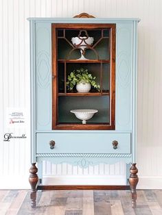 an old china cabinet painted blue with white flowers in the front and green leaves on top