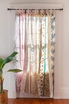 a potted plant sitting in front of a window with curtains hanging on the side