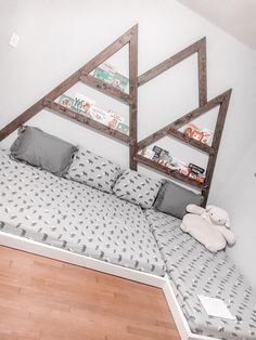 a bed with pillows and stuffed animals on it in a room that has white walls