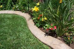 the flowers are blooming in the flowerbed by the sidewalk and grass lawn area