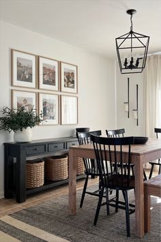 a dining room table and chairs with pictures on the wall above it, along with baskets