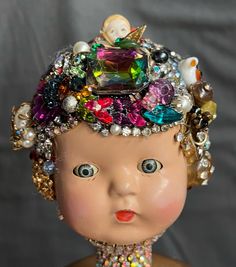 an old doll wearing a multicolored headpiece with pearls and other beads on it