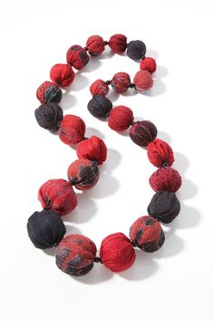 a red and black beaded necklace on a white background with space for the letter s