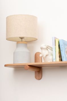 there is a shelf with books and a lamp on it next to a wall light