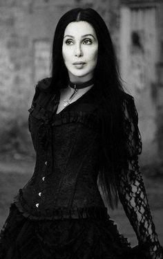 a woman with long black hair wearing a corset and posing for the camera