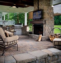 an outdoor living area with fireplace, chairs and television on top of the fire place