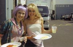 two women standing next to each other holding plates of food