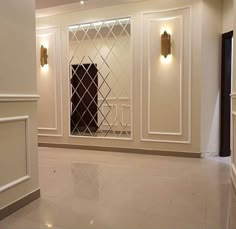 an empty room with white walls and gold trim on the doors, windows, and fireplace