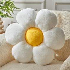 a white flower pillow sitting on top of a couch