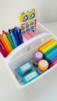 a white container filled with lots of different colored markers and crayons on top of a table