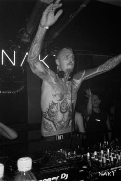 a man with tattoos standing in front of a dj set