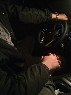 a man sitting in the driver's seat of a car with his hands on the steering wheel