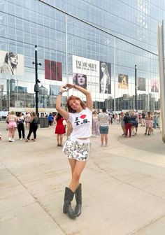 a young woman is dancing in front of a large building with many people around her