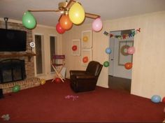 a living room decorated with balloons and streamers on the ceiling, along with a chair