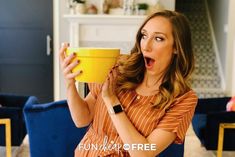 a woman is holding a yellow bowl in her hand and making a surprised face while sitting on a blue chair