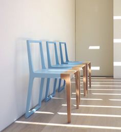 three blue chairs lined up against a white wall