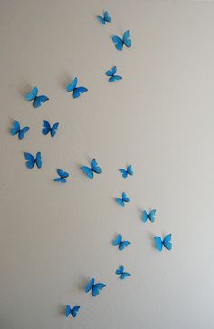 blue butterflies flying in the air on a white wall